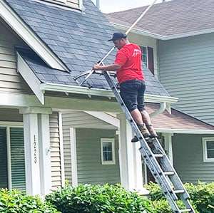 rainier employee cleaning roof and gutter